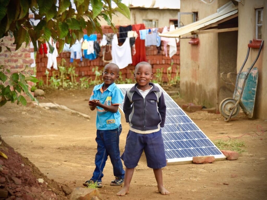 African children playing near solar panels in a rural community
